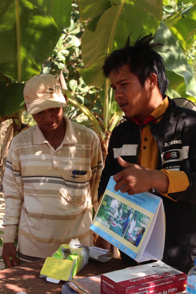 A member of our malaria outreach team demonstrates how to protect against malaria as another man looks on