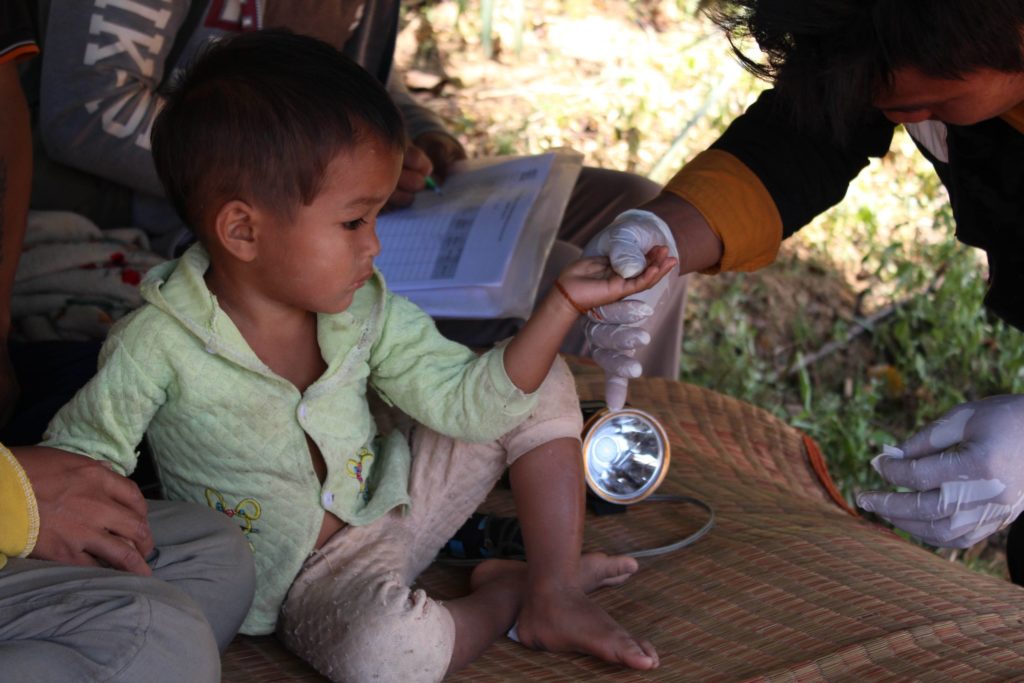 A small boy has a blood sample taken by a member of our malaria outreach team