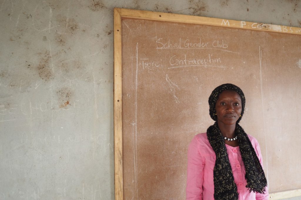 Teacher, Margaret, stands infront of the board in her classroom